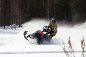 Athlete rides in the winter woods on a snowmobile.